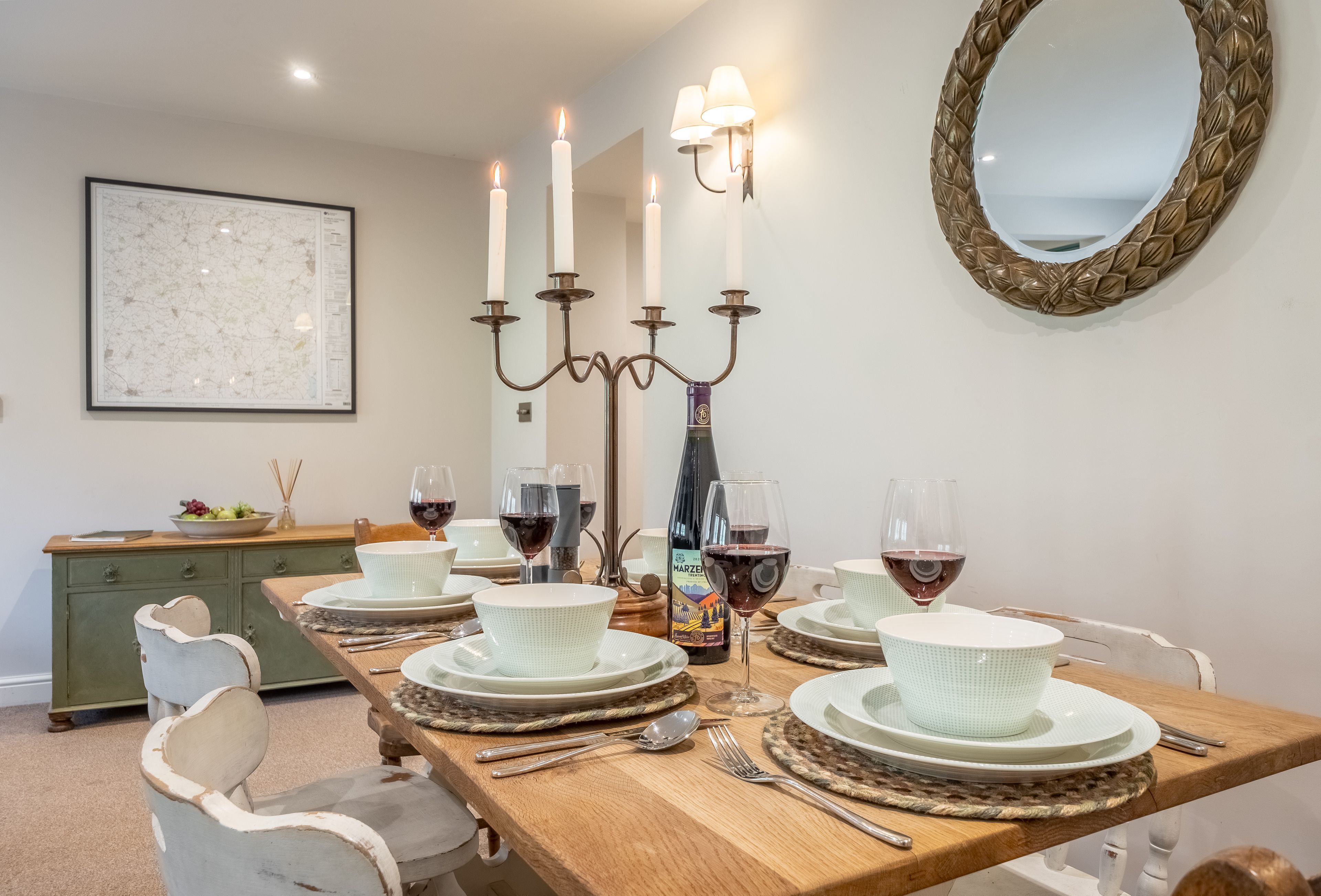 A dining room with a wooden table set for four, surrounded by white chairs.