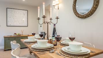 A dining room with a wooden table set for four, surrounded by white chairs.