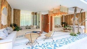 Un salon moderne avec un canapé, deux fauteuils en osier, une table basse et un sol à motifs.