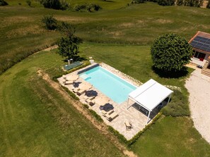 An aerial view of a swimming pool with a patio area, surrounded by grass and trees. - Villa Edelia, Villa for exclusive use in Mondavio, Le Marche (Mondavio)