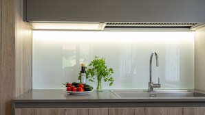 A kitchen with a modern faucet, a plate of tomatoes and cucumbers, a bottle of olive oil, and a green plant. - Villa Edelia, Villa for exclusive use in Mondavio, Le Marche (Mondavio)