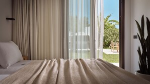 Un dormitorio con cama, cortinas translúcidas y vistas al exterior.