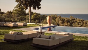 Un área junto a la piscina con sillones de descanso y un jarrón grande.