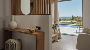 Una sala de estar moderna con una consola de madera, un espejo grande y vistas a una piscina y follaje.