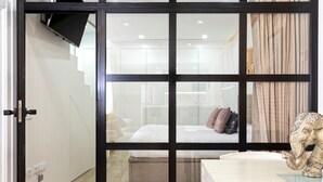 Et moderne hotelværelse med en skydedør, en seng med puder, et natbord og en dekorativ elefantfigur.
