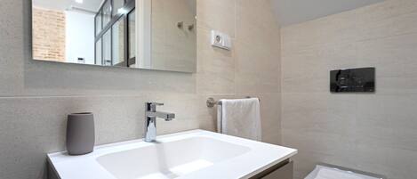 A modern bathroom with a white sink, a mirror, a towel rack, and a toilet.