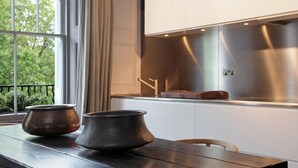 Cozinha moderna com mesa de madeira, duas panelas de metal e um exaustor de aço inoxidável.