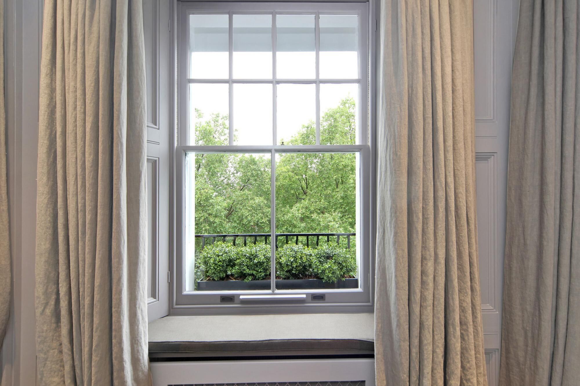 A window with a view of greenery and a balcony railing.