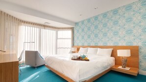 Et moderne hotelværelse med en stor seng, et skrivebord og en stol.