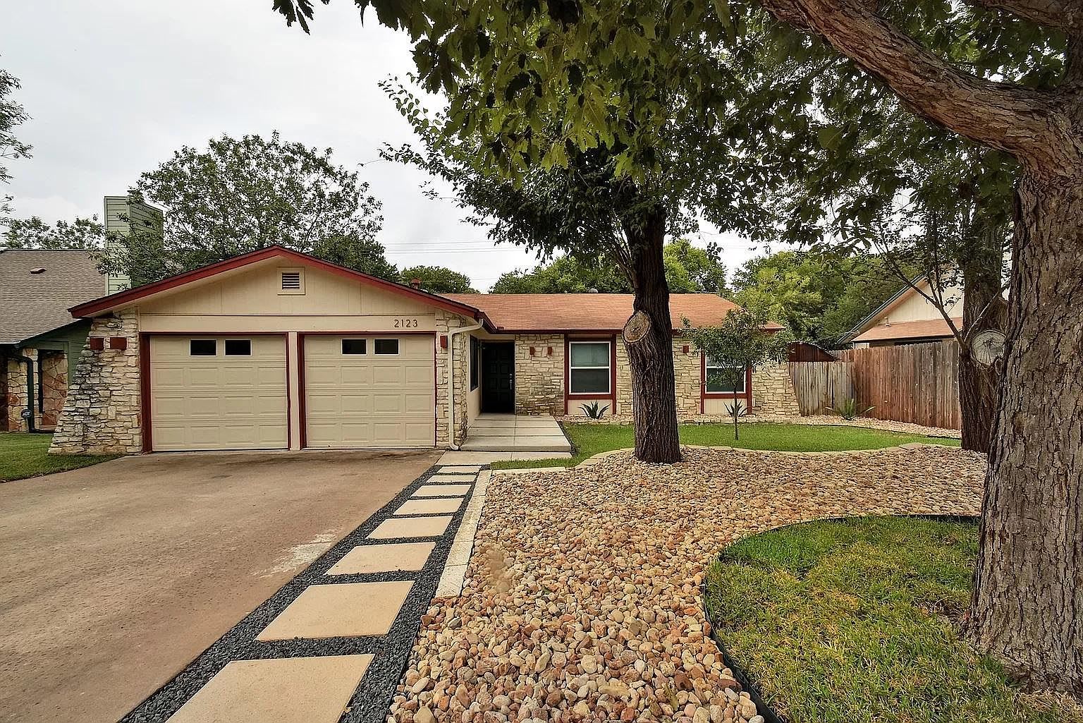 A residential house with a garage, stone facade, and a driveway leading to the entrance.
