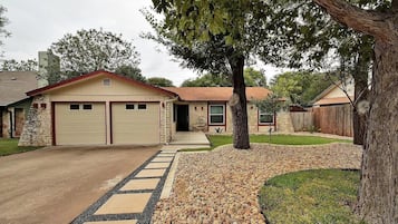 A residential house with a garage, stone facade, and a driveway leading to the entrance.