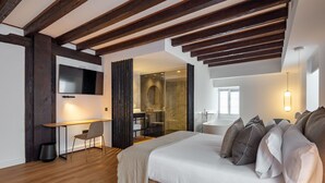 Una habitación de hotel moderna con una cama grande, un escritorio y una zona de ducha.