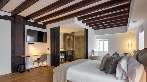 A modern hotel room with a large bed, a desk, and a shower area. - EtxeAundi Hotel Boutique (Oñati)