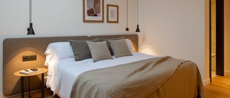 A modern bedroom with a large bed, a bedside table, and two pendant lights.