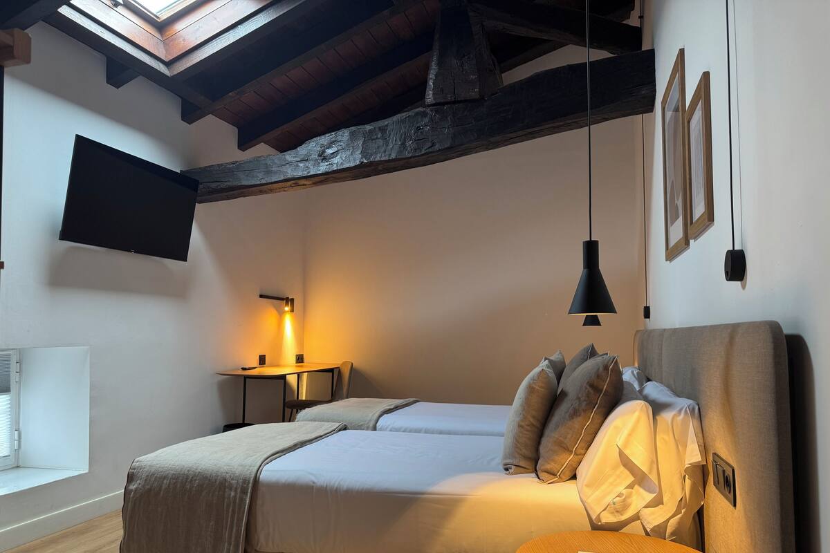 A bedroom with a bed, bedside table, and a TV mounted on the wall.