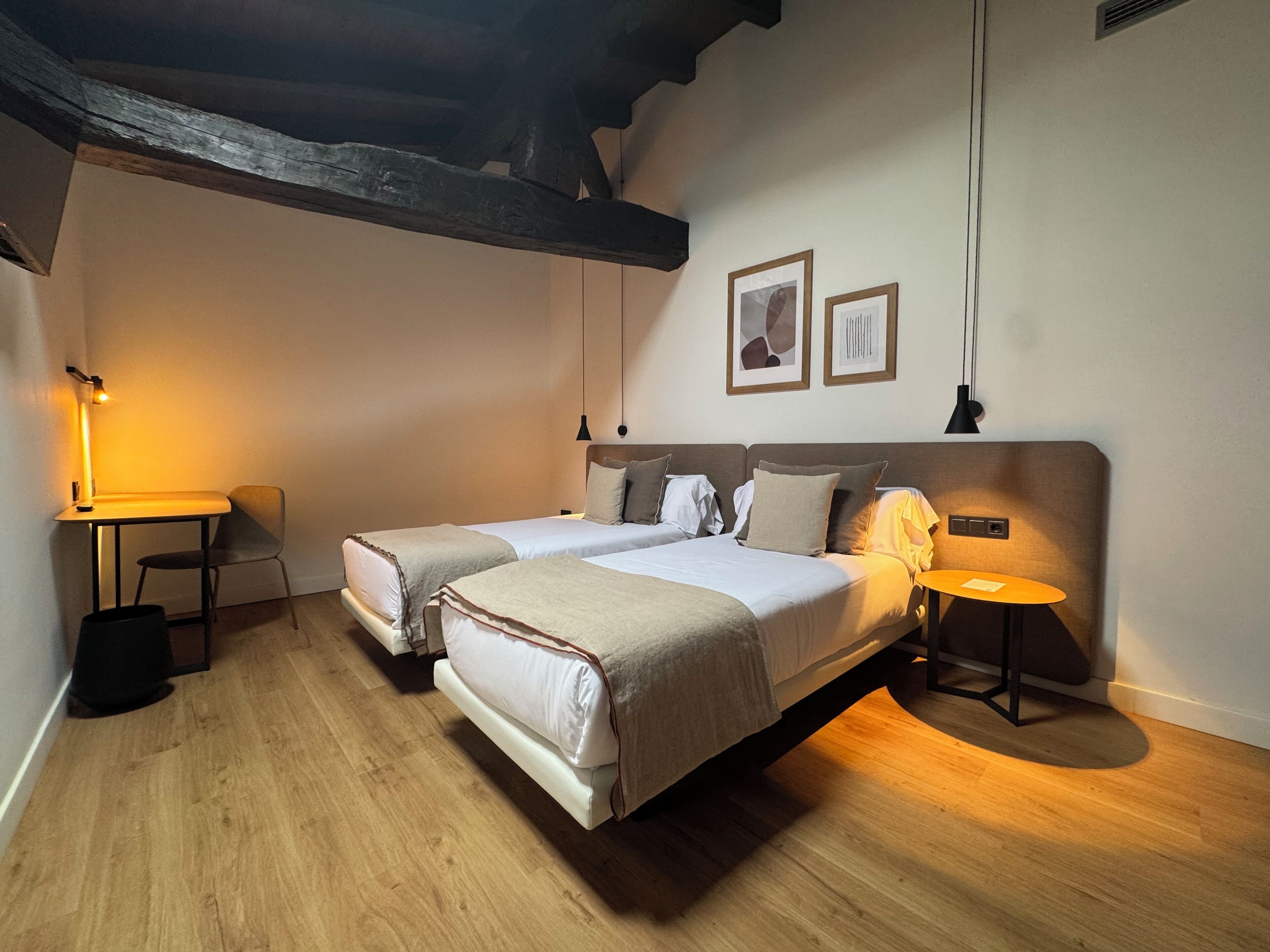 A bedroom with two beds, a desk, and a small table.