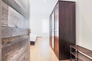 A room with a wooden door, a wardrobe, a bed, and a bench. - Ω Lucid StayΩ By Olympic Stadium,Botanical Garden (Montréal)
