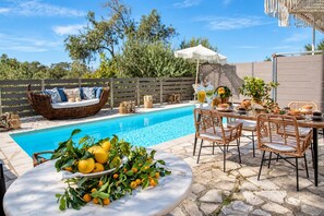 A poolside area with a wicker sofa, dining table, and a bowl of lemons. - Dimitris Cottage - Two Bedroom Villa, Sleeps 4 (Apergatika)