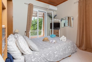 A bedroom with a bed, a wardrobe, a mirror, and a balcony with curtains. - Dimitris Cottage - Two Bedroom Villa, Sleeps 4 (Apergatika)