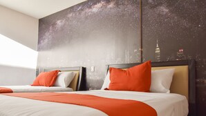 Ein Hotelzimmer mit zwei Betten, jeweils mit weißer und orangefarbener Bettwäsche, und einem großen Wandbild, das einen sternenübersäten Nachthimmel und eine Stadtansicht zeigt.