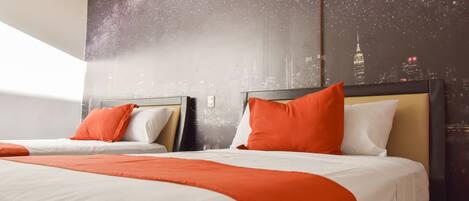 A hotel room with two beds, each with white and orange bedding, and a large wall mural depicting a starry night sky and city skyline.