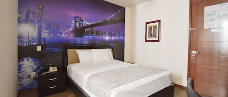 A bedroom with a bed, a nightstand, a ceiling fan, a door with a notice, and a cityscape mural on the wall.