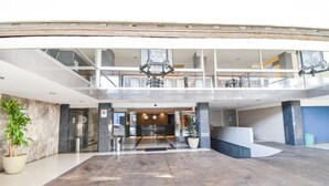 Eine geräumige Lobby mit hoher Decke, einer Rezeption und einer Sitzecke.