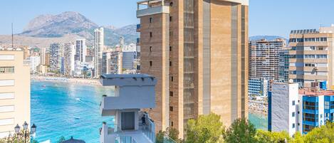 Un edificio alto con balcón que da a una playa y al mar.