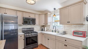 A modern kitchen with stainless steel appliances, light wood cabinets, and a red toaster. - Flex Comfort Apts of Westchester #2 (Rye Brook)