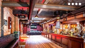 A bar with wooden floors, brick walls, and a long counter with various bottles. - Flex Comfort Apts of Westchester #2 (Rye Brook)