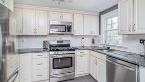 Una cocina moderna con armarios blancos, electrodomésticos de acero inoxidable y encimera de granito.