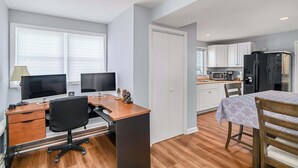 A compact living space with a kitchenette, a dining area, and a workspace with two monitors. - Flex Comfort Apts of Greenwich #1 (Greenwich)