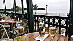 An outdoor dining area with tables, chairs, and a view of a body of water.