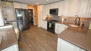 A modern kitchen with white cabinets, stainless steel appliances, and a patterned backsplash.