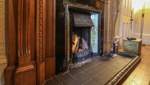 A fireplace with intricate woodwork and a tiled floor.