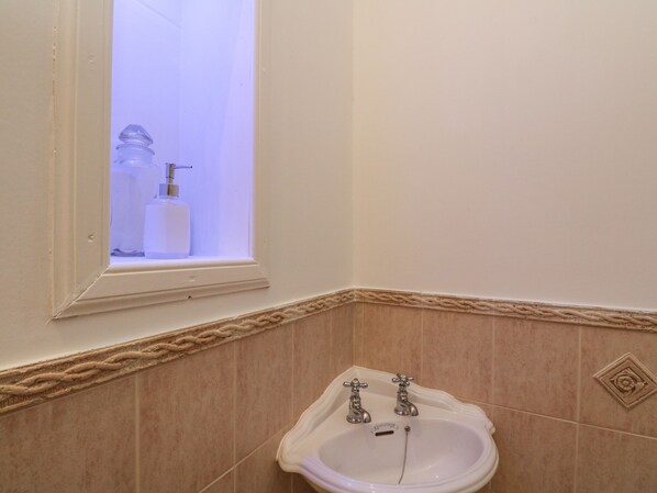 Un baño con lavamanos, dos grifos y una ventana.
