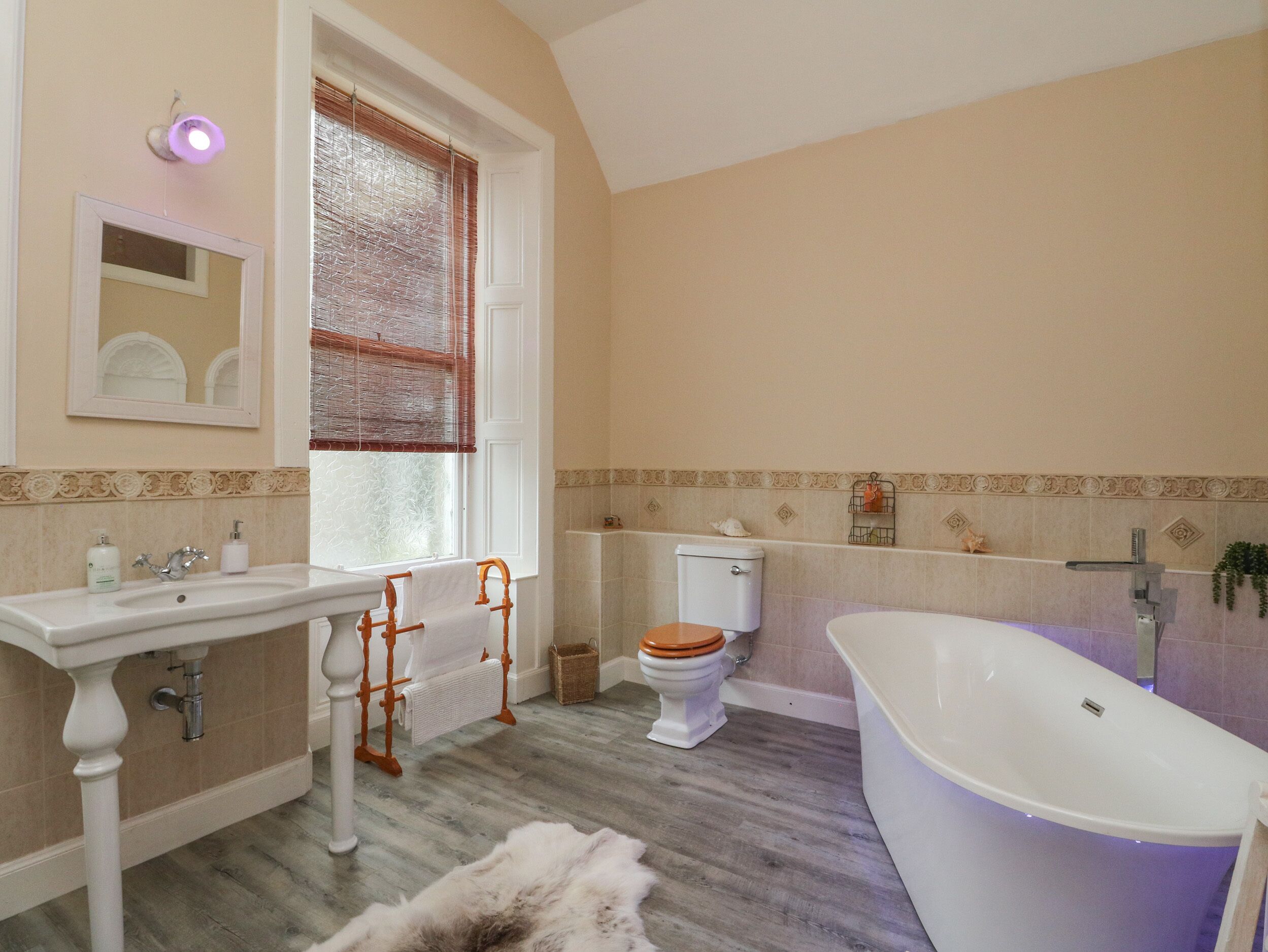 A bathroom with a white sink, wooden vanity, a white toilet, and a freestanding bathtub.