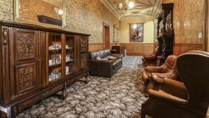 A formal room with a large wooden cabinet, leather armchairs, and a patterned carpet.