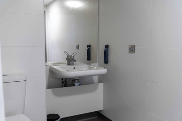 Un baño con lavamanos, espejo y retrete blancos.