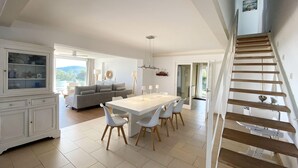 A spacious living area with a dining table, white chairs, a grey sofa, and a staircase. - Holiday rental villa with swimming pool in Begur, Casa de Campo (Begur)