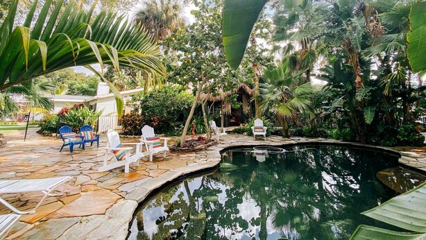 Une piscine entourée de plantes tropicales et de dalles de pierre.