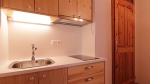 A kitchen with wooden cabinets, a stainless steel sink, and a built-in range hood.