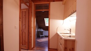 A narrow hallway leading to a kitchen with wooden cabinets and a sink.