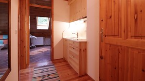 A narrow wooden hallway with a kitchen area featuring wooden cabinets and a sink.