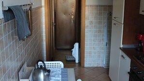 Une cuisine compacte avec une table à manger, une bouilloire et une horloge au mur.