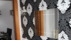 Un coin repas avec une table noire, des chaises et un mur décoratif agrémenté d’un miroir.