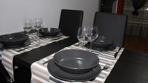 Une table à manger dressée avec des assiettes noires, des verres à vin et des couverts, le tout posé sur une nappe à rayures.