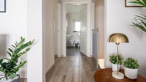 A hallway with a wooden floor, a radiator, a lamp, and potted plants. - The Faenza Apartment (Firenze)