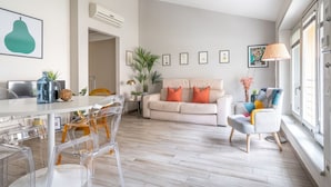 A modern living room with a sofa, chairs, a dining table, and a large window. - The Faenza Apartment (Firenze)