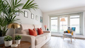 A modern living room with a beige sofa, a round wooden coffee table, a floor lamp, and a colorful armchair. - The Faenza Apartment (Firenze)